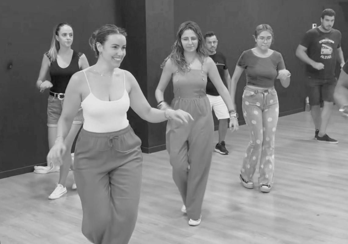 Grupo de alumnos principiantes riendo en clase de salsa en Málaga ambiente divertido.
